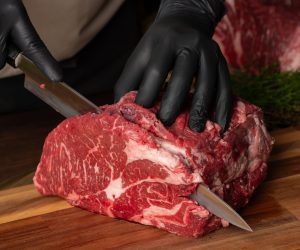 The,Butcher,Wearing,Black,Gloves,Cuts,The,Meat,With,Knife